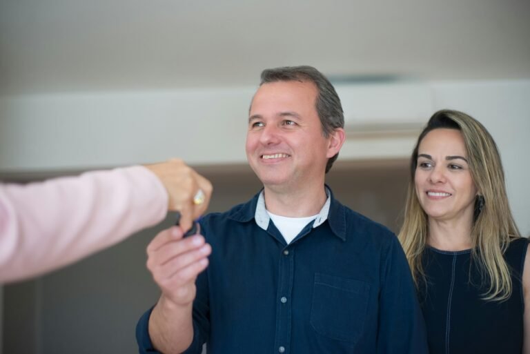 Smiling couple receiving keys, celebrating new home purchase indoors.