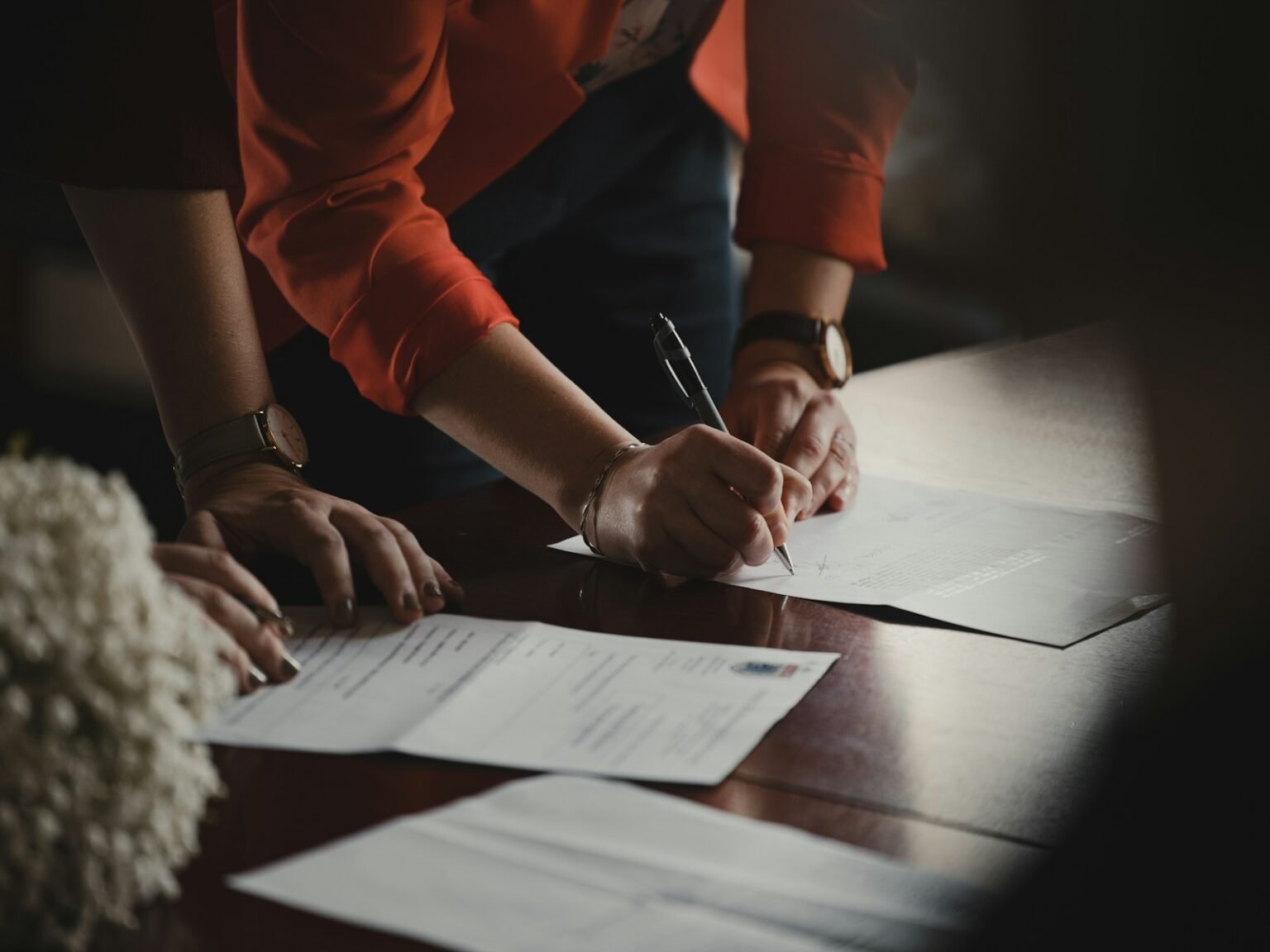 People reviewing and signing documents on a table